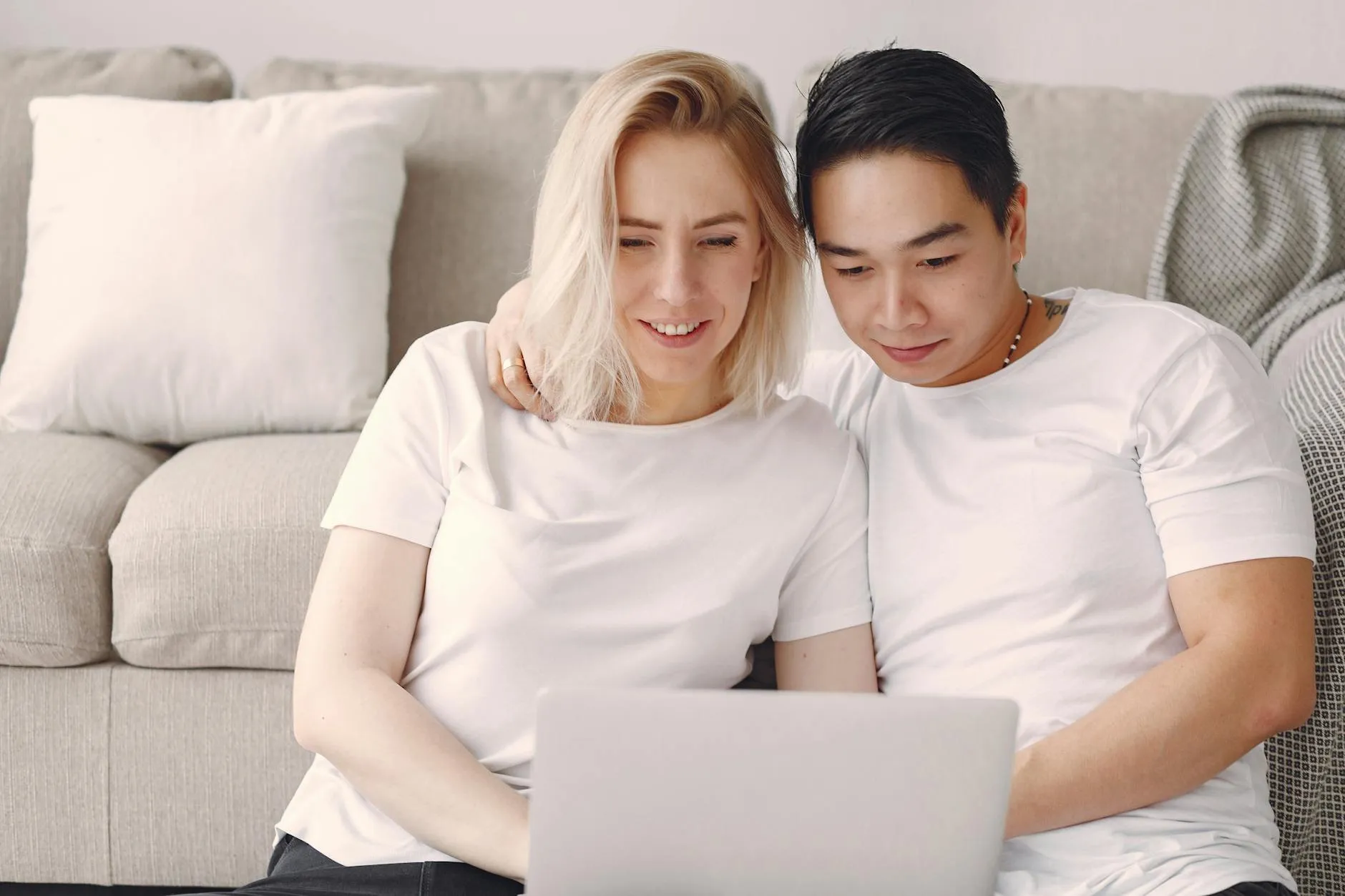 Couple sitting together on a sofa looking at a laptop while planning their wedding