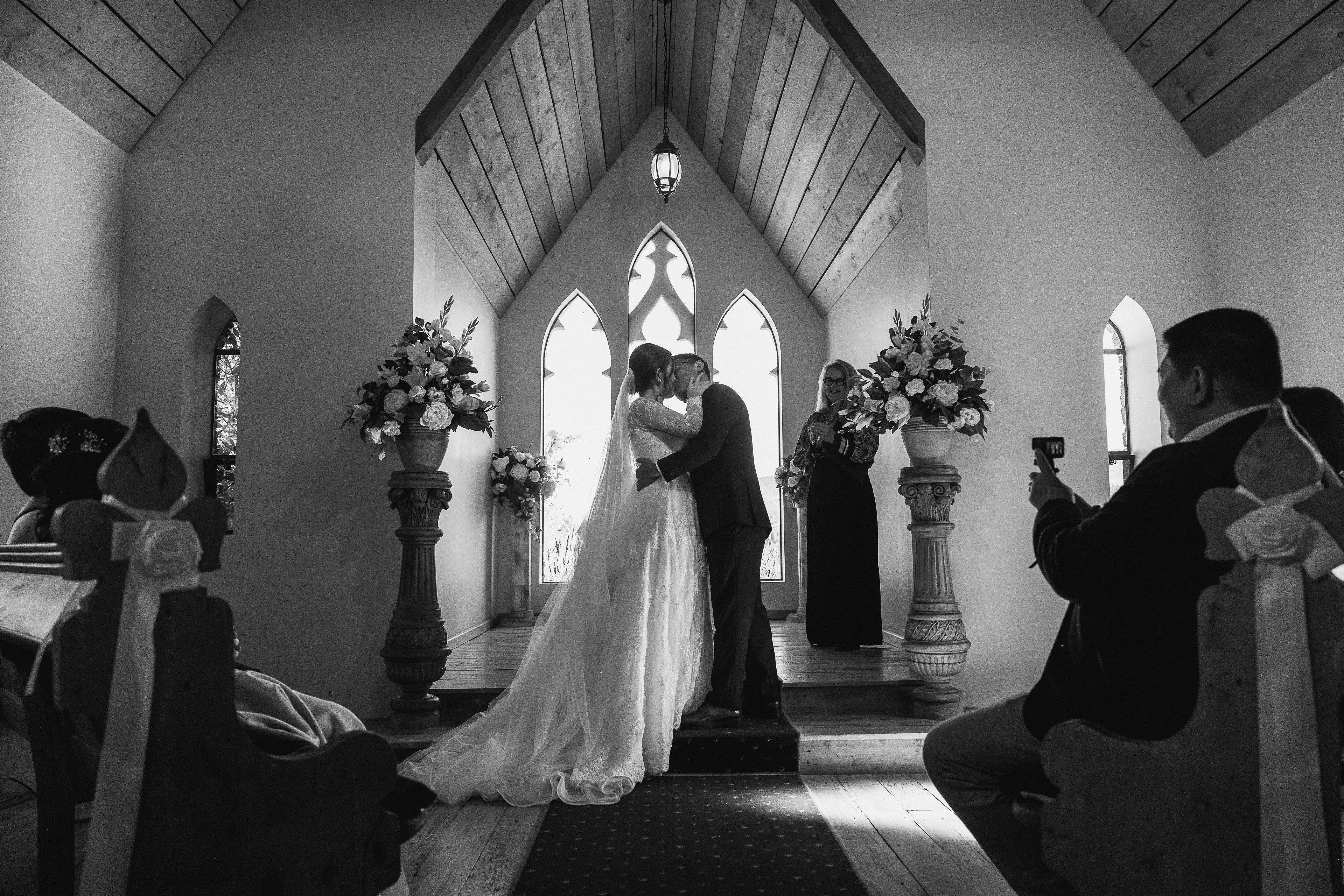 A bride and groom sharing their first kiss inside Chapel by the Lake, Queenstown