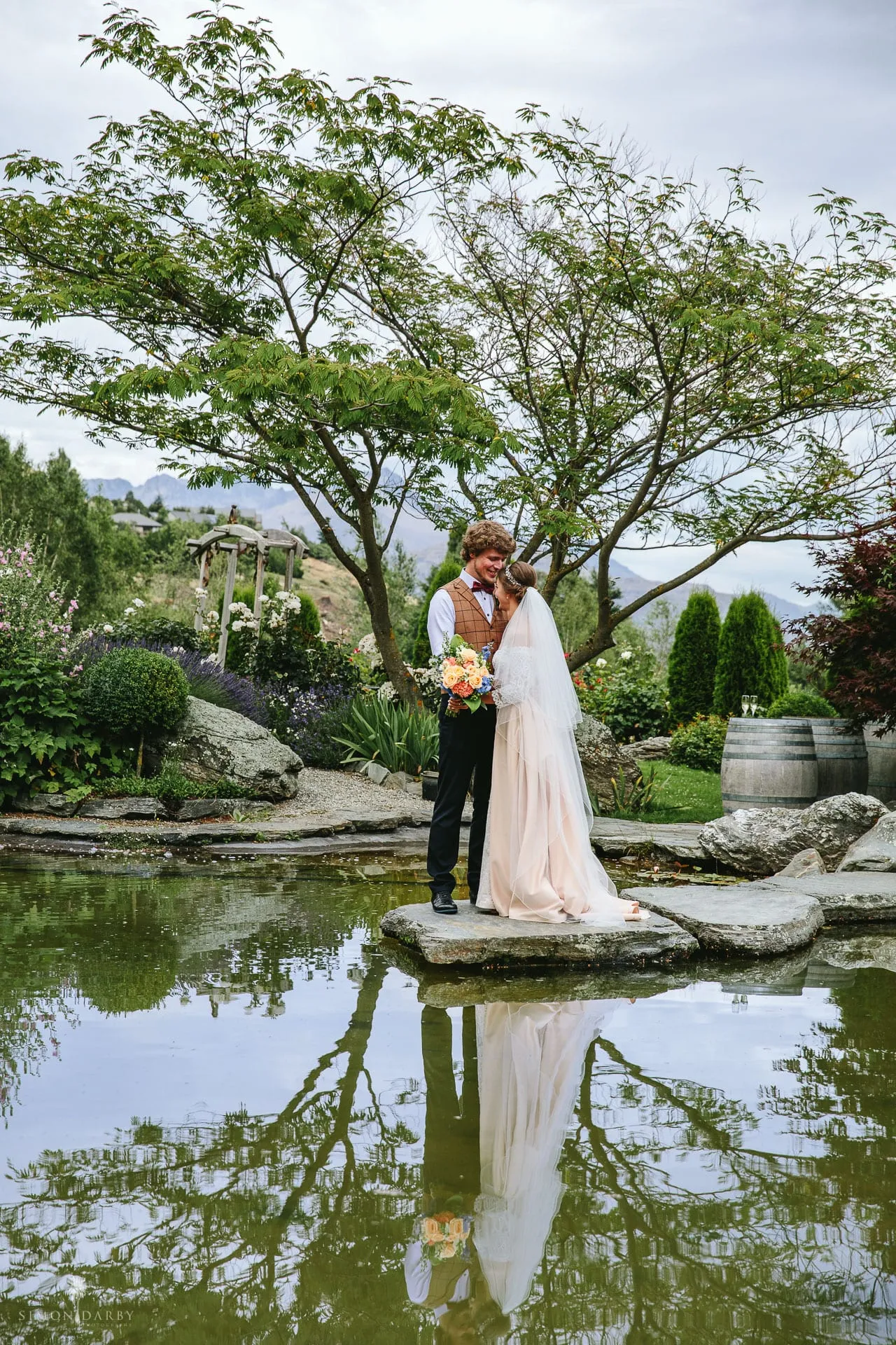 A bride and groom by the garden pond at Stoneridge Estate, Chapel by the Lake