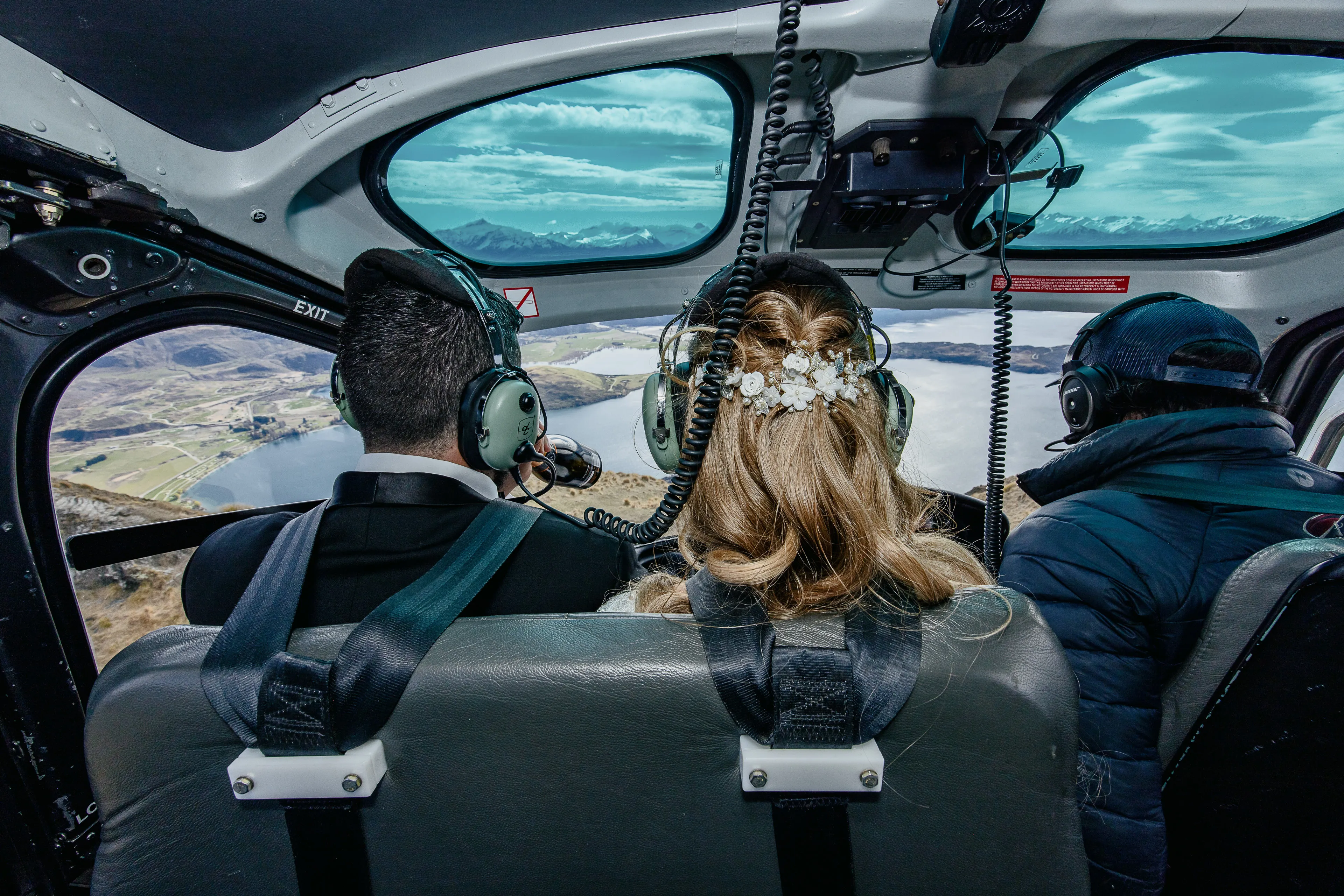A bride and groom on a scenic helicopter flight over Lake Wānaka to their Coromandel Peak wedding