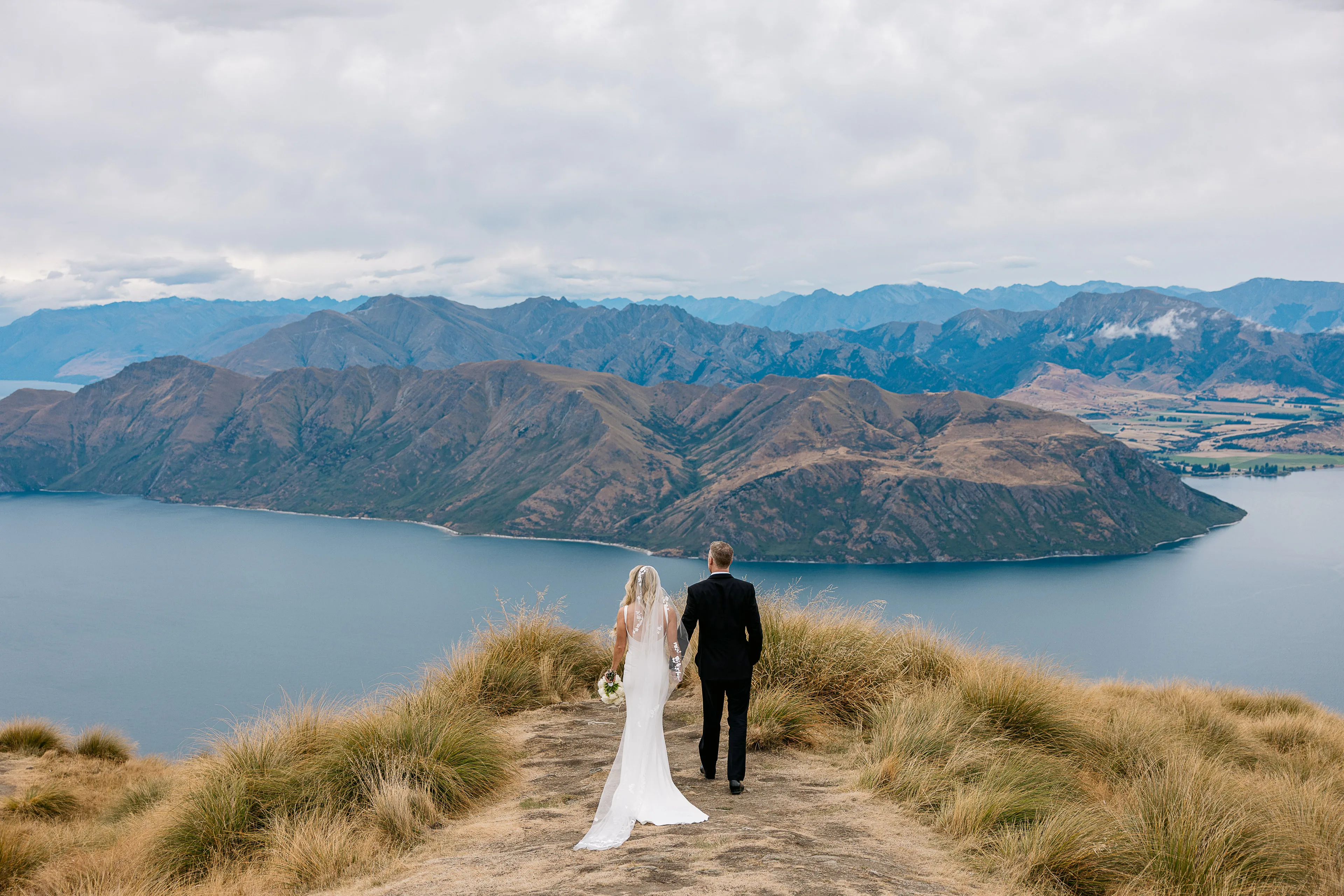 Newlyweds taking in the view over Lake Wānaka from the top of Coromandel Peak