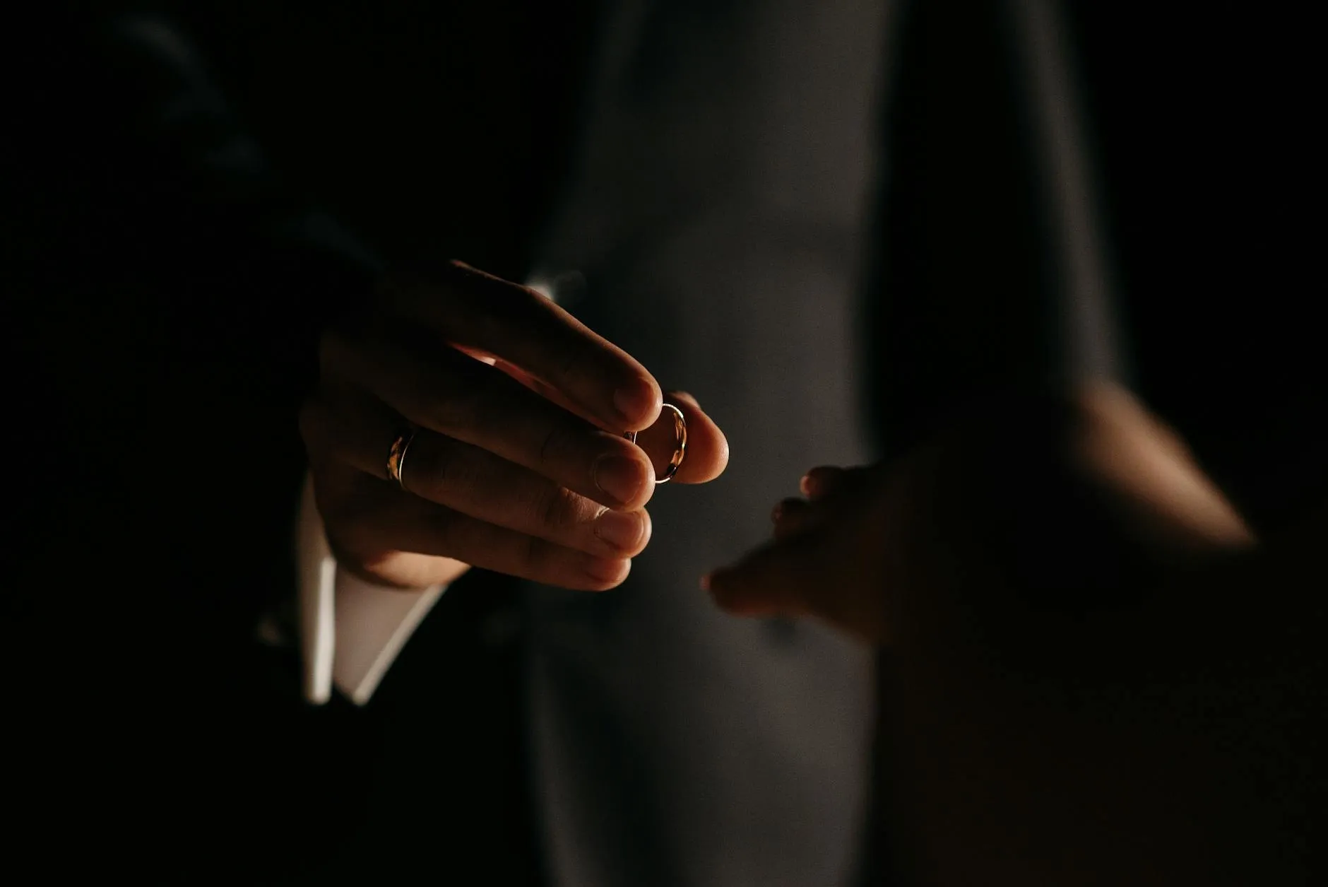 Two hands with wedding rings touching in low light