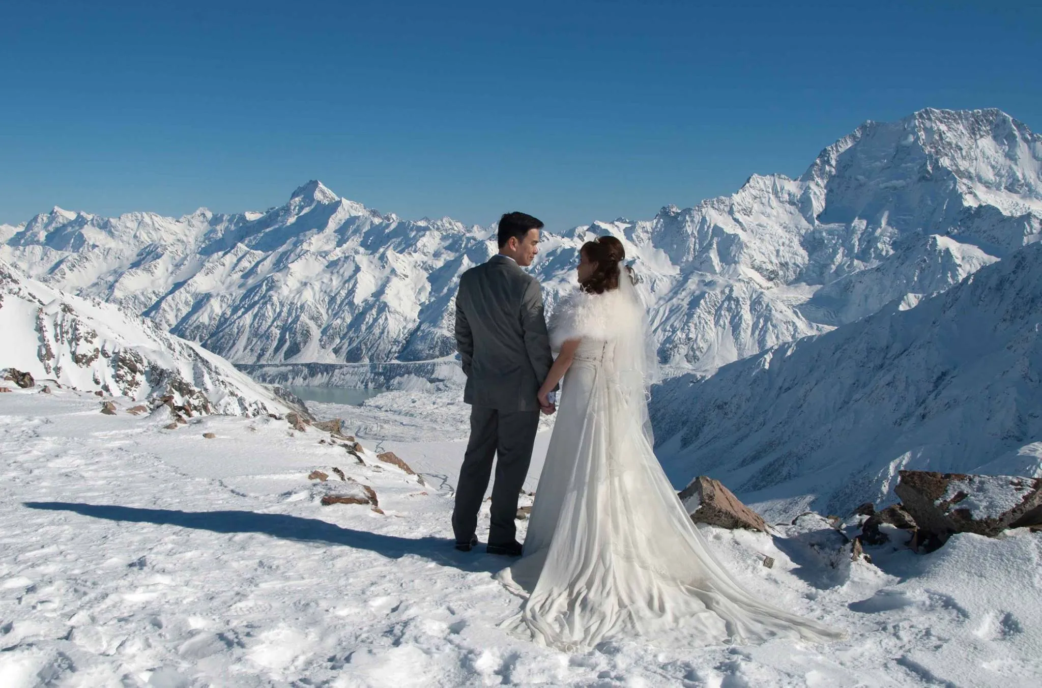 A couple taking in the panoramic glacier and mountain views from Liebig Dome, Aoraki / Mt Cook National Park