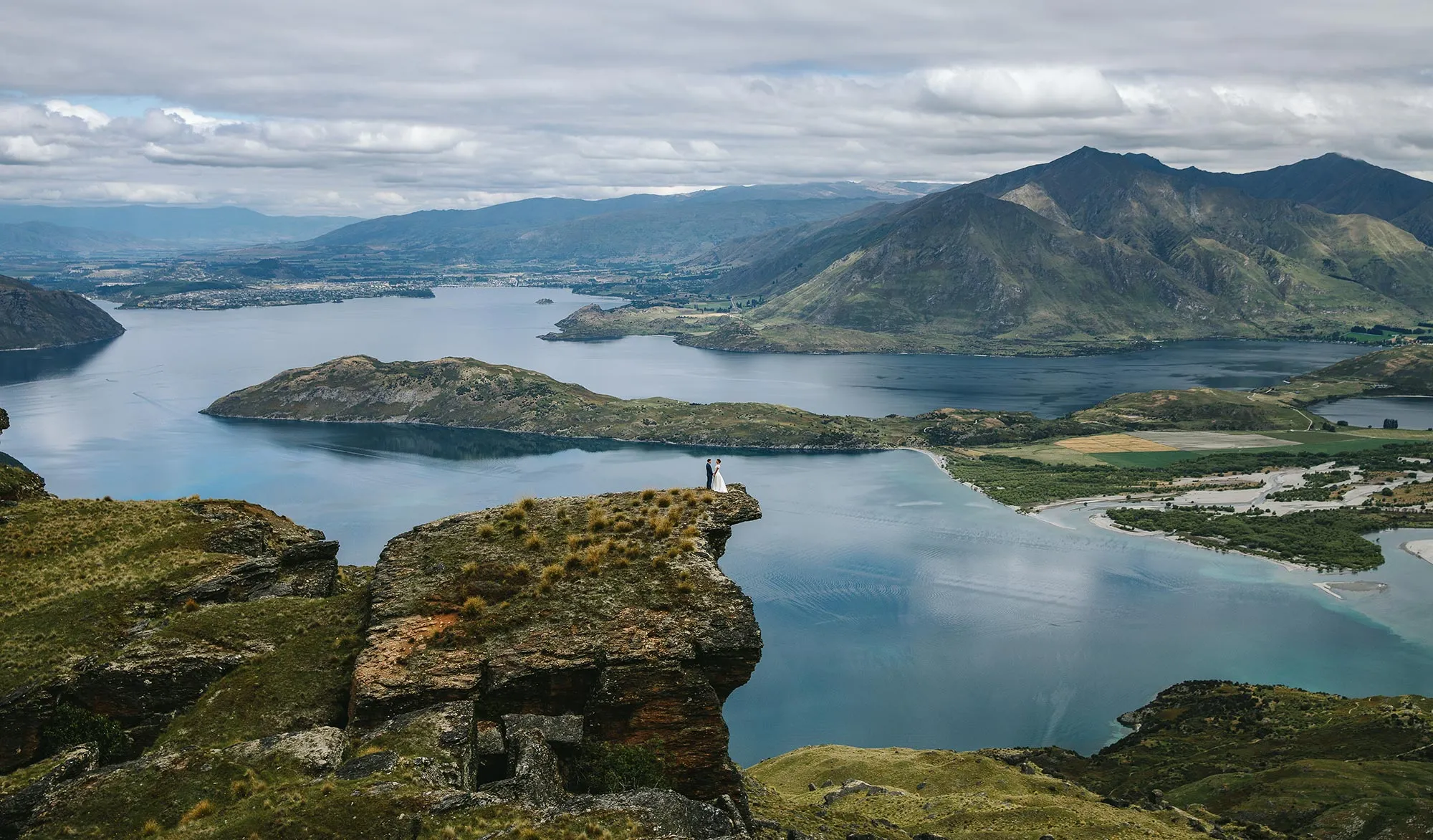 A couple on the dramatic Lookout Hill clifftop with panoramic views across Lake Wānaka