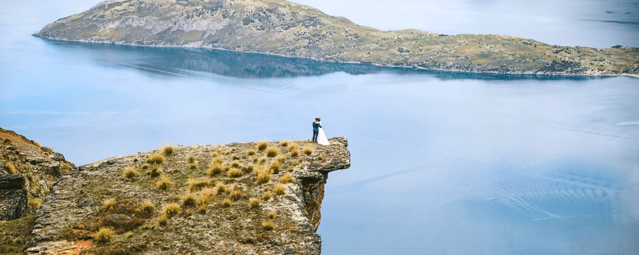 A couple embracing on the edge of Lookout Hill high above Lake Wānaka