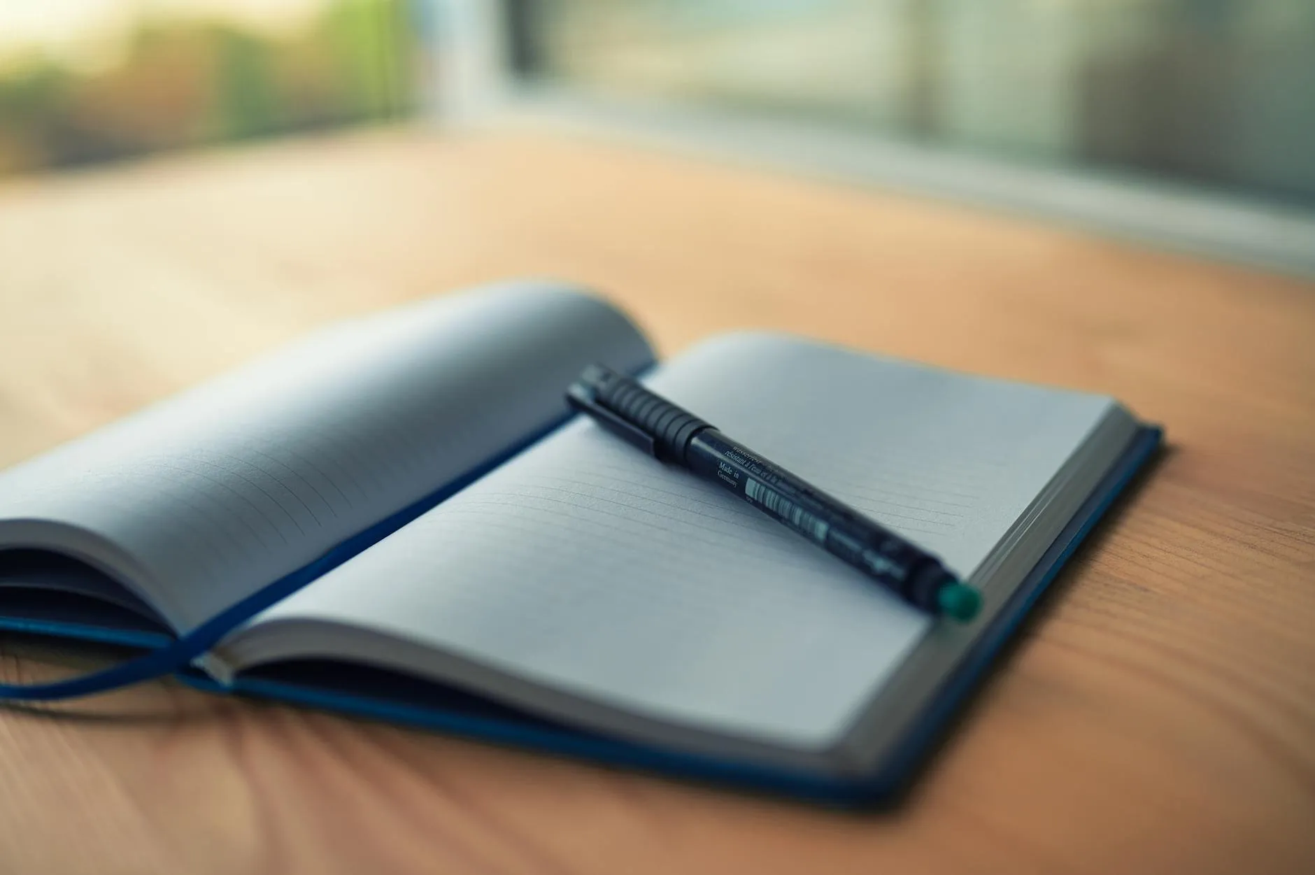 Open notebook and pen on a wooden desk in soft light