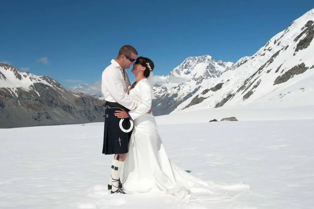 A bride and groom embracing on Richardson Glacier with Aoraki / Mt Cook behind them