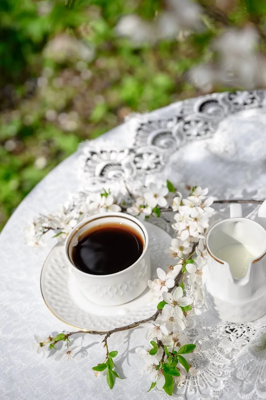 Cup of black coffee and spring blossom on a white garden table