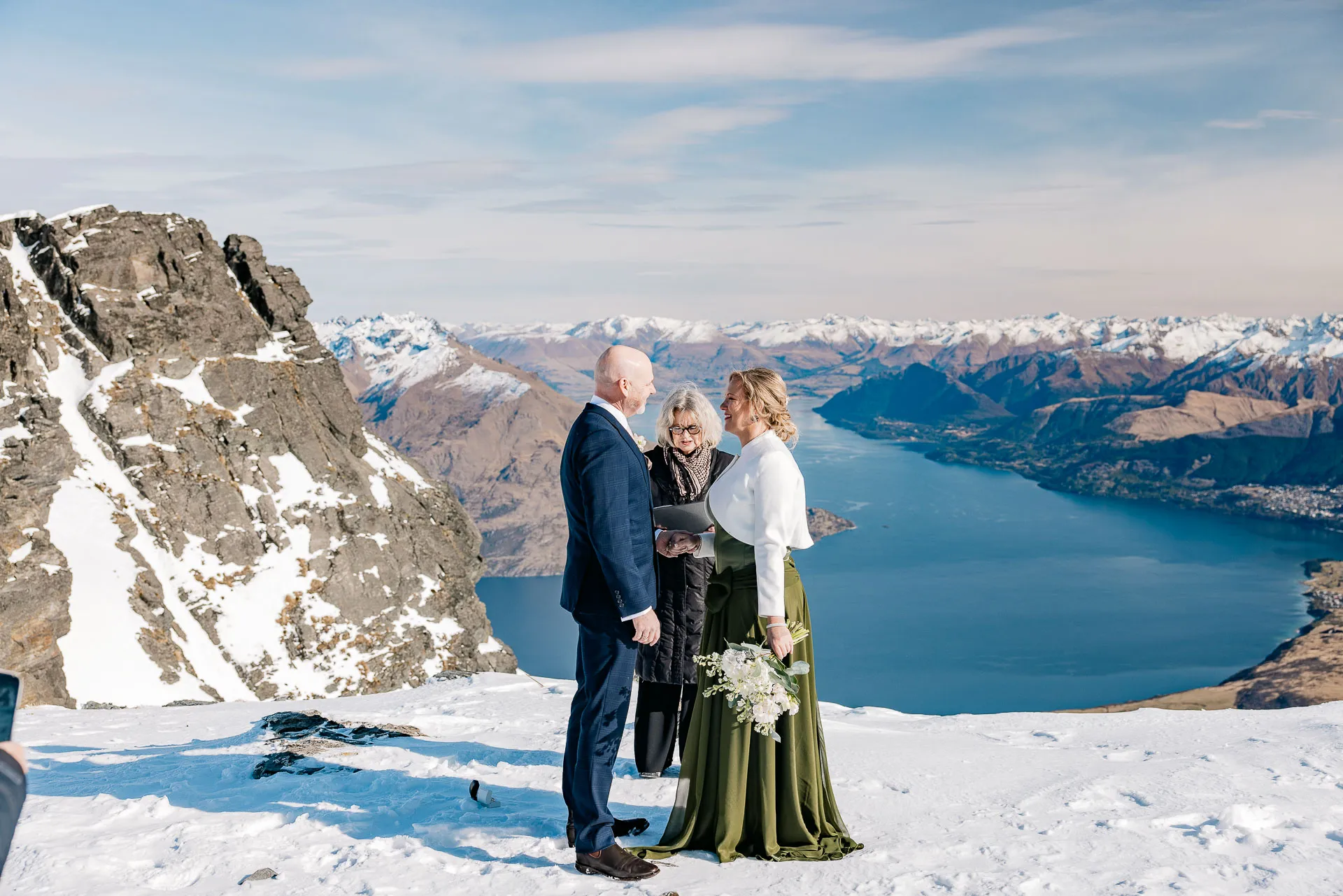 A couple exchanging vows with their celebrant on The Remarkables, high above Lake Wakatipu and Queenstown