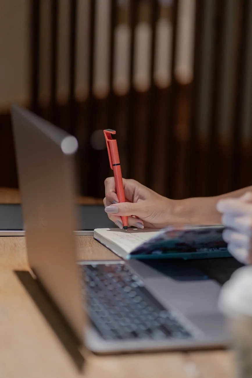 Hand writing notes beside a laptop at a planning desk