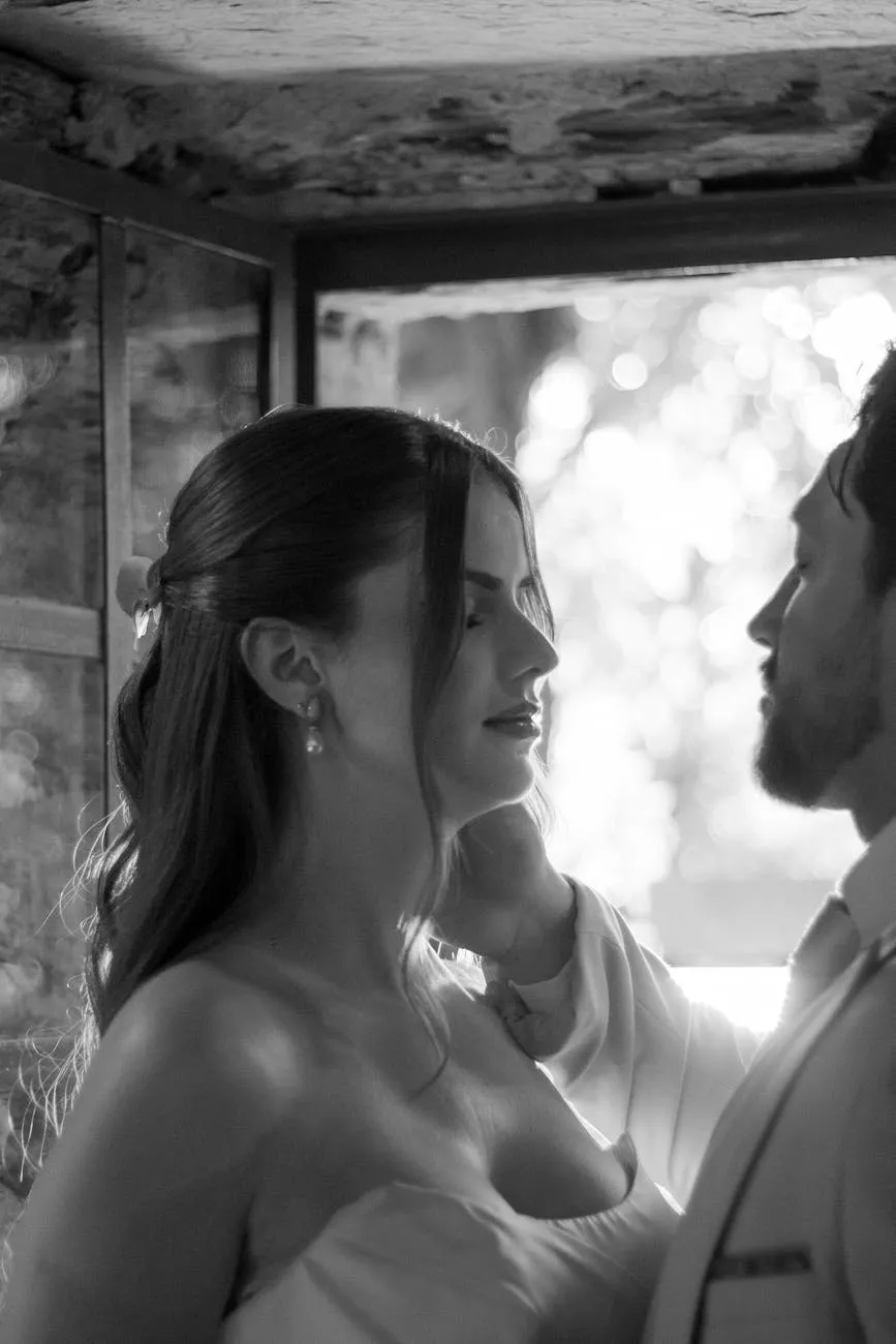 Bride and groom standing close together in soft window light, black and white