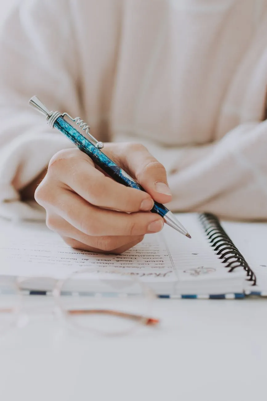Hand writing in a planner notebook with a blue pen