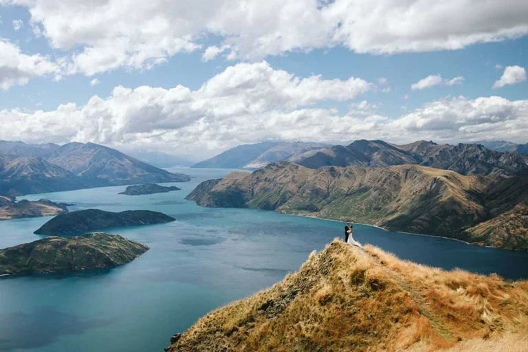 Couple standing at Coromandel Peak overlooking Lake Wānaka during a helicopter elopement